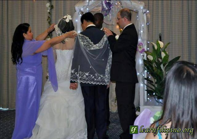 In a Filipino wedding, parts of the ceremony are the placing of veil and cord by the Sponsors. Veil – It is a symbol of purity. It symbolizes the presence of the Lord. It is placed over the shoulders of the couple to symbolize their union and being “clothed as one” in unity. Cord – It is a symbol of the couple’s bond; that they are no longer two but one in their new life as a couple.